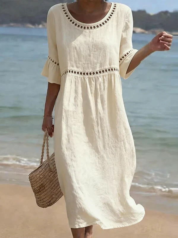 Kobieta w kremowej sukience midi z ażurową wstawką na plaży